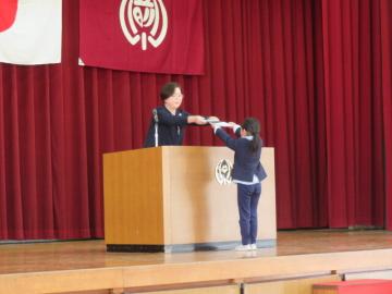 1年生を代表して体育館のステージで校長から修了証を受け取る児童