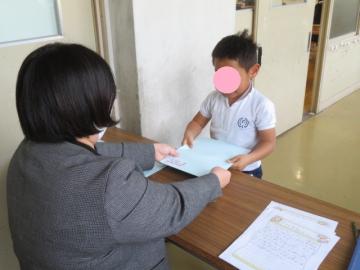 ろうかでひとりずつ修了証を受け取る1年生