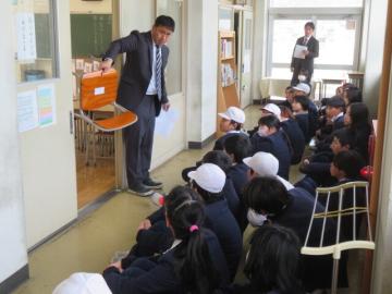 5年生に、つくえといすに貼られた指示書の見方を説明する担当教諭