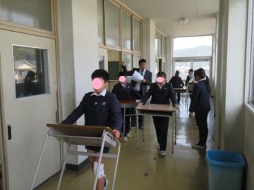 つくえといすをかかえて廊下を移動する5年生