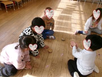 3歳児が教室の床でこままわしをしているところ