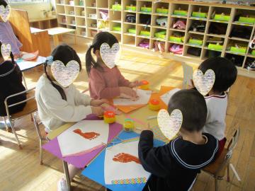 4歳児が教室でテーブルでグループを作って絵馬をつくっているところ