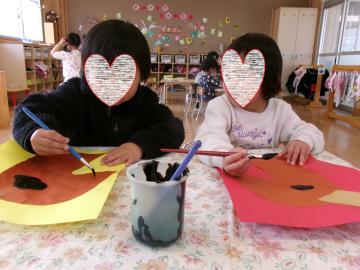 3歳児が教室で画用紙に筆で絵をかいているところ