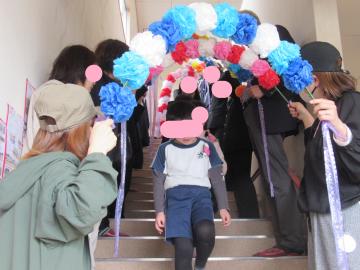 ご来賓・地域の皆さんがつくってくれた花道を通る修了児1