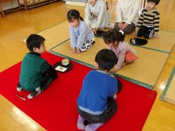お茶を運ぶ幼児とお茶をいただく幼児がお辞儀し合っている様子