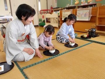 幼児が茶道先生に教えてもらいながらお茶をたてる様子