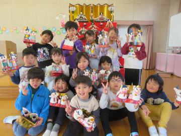 園児がひな人形を持って写真撮影している様子