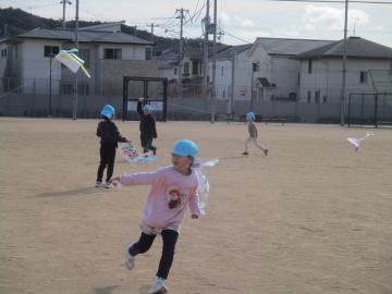 園庭で、凧揚げで遊んでいる5歳児たちの様子