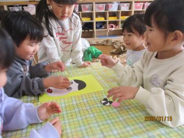 室内で、福笑いで遊んでいる園児たちの様子