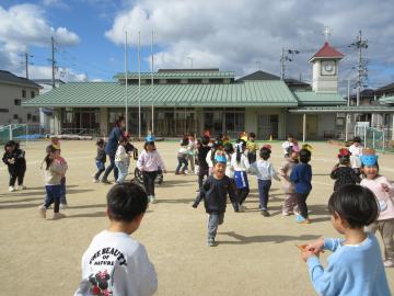 園庭で、元気に走りながら、鬼役の友達に豆を投げている園児たちの様子