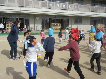 園庭で、鬼役の友達に豆を投げている園児たちの様子