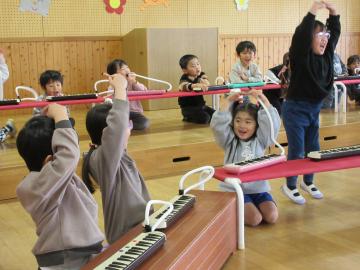 遊戯室で、鍵盤ハーモニカクイズを出している園児たちの様子