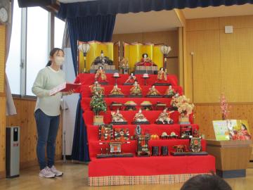 遊戯室で、教員が雛飾りの話をしている様子