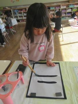 4歳児が室内で書初めをしている様子