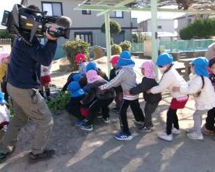 屋外で園児たちがダイコンの収穫をしている様子