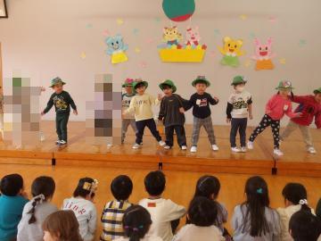 遊戯室のステージ上で歌いながら踊る3歳児