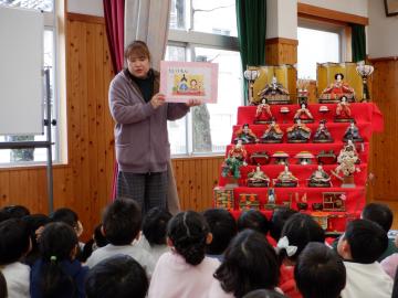 園長先生が紙芝居を持ちながら話して、その話を座って聞く幼児たち