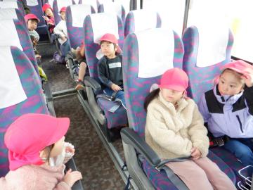 大型バスのシートに友達と一緒に座って、楽しそうに話をしている幼児