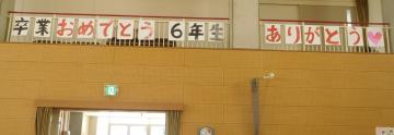 体育館で子どもたちが活動している写真。後ろに、卒業おめでとうの文字があります。