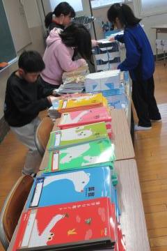 今から配布する沢山のノートと教科書が山積みされた様子