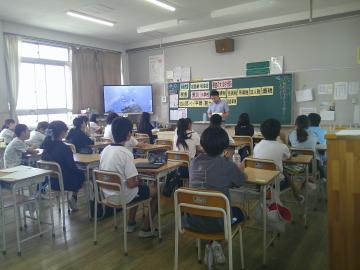 教室で自席に座って先生から税金についての授業を聞いている児童たちのようす