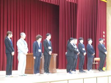 体育館の壇上で着任された先生が挨拶をする様子