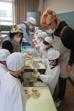 1年生が先生方と一緒に給食の準備をしている様子