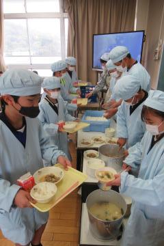 6年生給食当番が配膳をしている様子