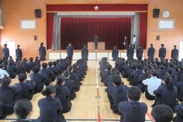 学級委員長の代表がステージに上がり校長先生から任命書を手渡されている様子