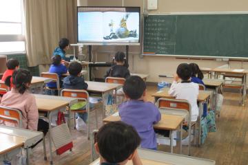 担任の先生が1年生に絵本の読み聞かせをしている様子