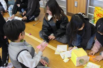 1年生が2年生におもちゃを見せてもらっている。