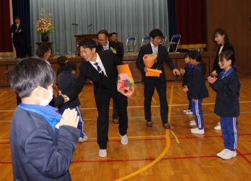 体育館フロアーで児童が作った花道を通る離任の先生たち