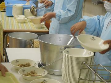 銀色の入れ物から食事を入れている様子