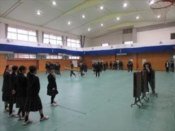 体育館の床にシートを引く生徒の様子
