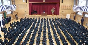 体育館の壇上で校長が話をする様子