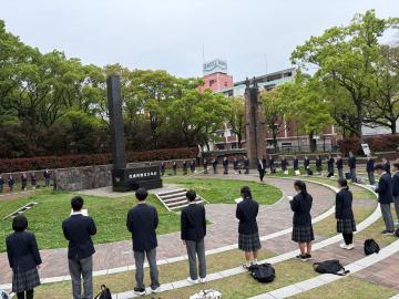 学生たちが記念碑の前の円形の広場に並んで立ち黙祷している様子