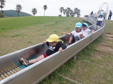 長いローラー滑り台を連なって滑る子供たち