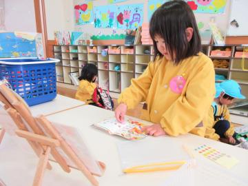室内でシール帳にシールを貼る女児