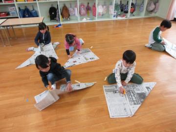 保育室で新聞紙を使い、兜をつくっている様子