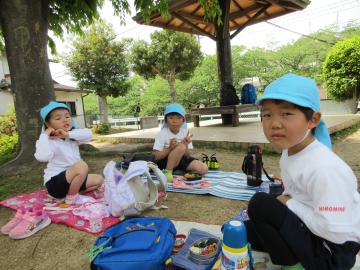 公園でレジャーシートを広げ、お弁当を友達と一緒に食べている様子