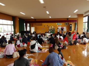 遊戯室でこいのぼりの作り方の説明を聞いている園児たちの様子