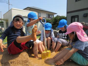 園庭で泥遊びをしながら泥の感触を味わっている様子