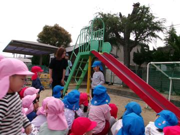 園庭で5歳児が3歳児と4歳児に遊具の遊び方を説明している様子