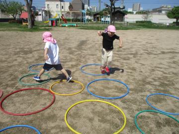 フラフープを飛び越えて遊んでいる園児たちの様子