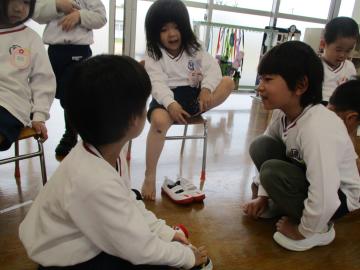 年長児が年少児に靴下の履き方を教えている様子