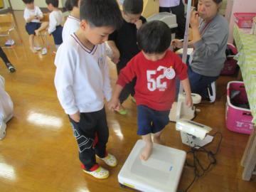 年長児が年少児を体重計の場所へ連れて行っている様子