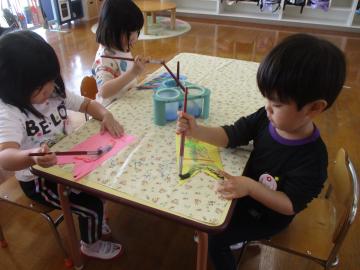こいのぼりの形をした画用紙に絵の具を塗っている園児たちの様子