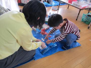 親子でビニール袋を使ってこいのぼりをつくっている園児たちの様子