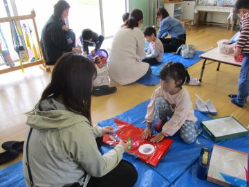 いろいろな素材を使って、親子でこいのぼりをつくっている園児たちの様子