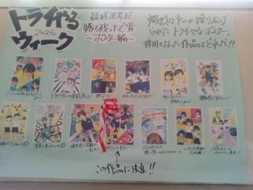 手書きの見出しと複数のカラフルな漫画風の小さなポスターが並び中央に赤いリボンが付いた掲示板の写真